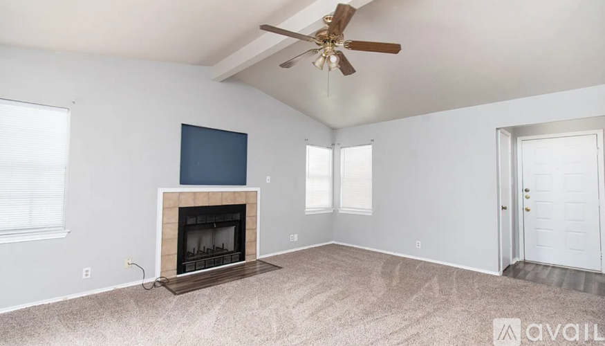A living room with a fireplace and a ceiling fan.