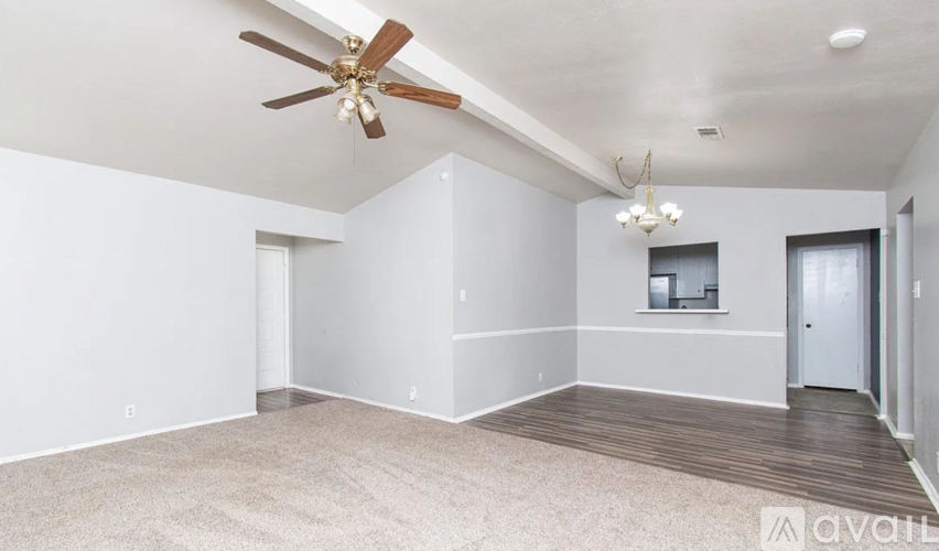 A spacious room with a ceiling fan and a chandelier.