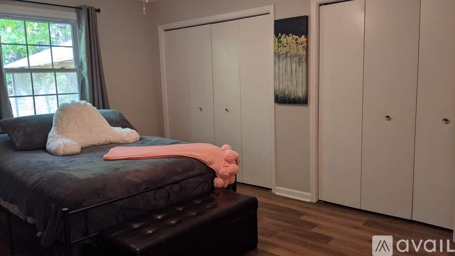 A bedroom with a black bed and a pink pillow.