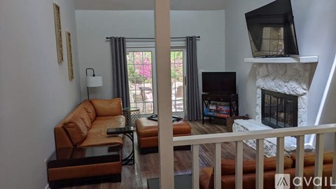 A living room with a brown leather couch and a television on a stand.