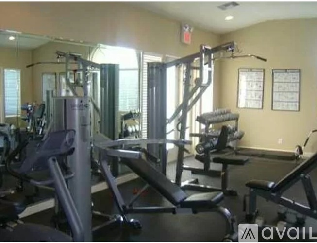 A gym with a mirror, weights, and cardio equipment.