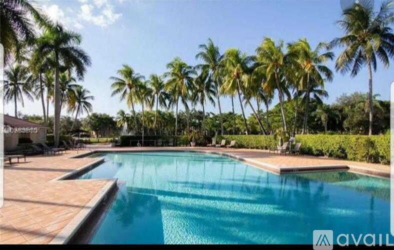 A pool surrounded by palm trees under a clear sky.