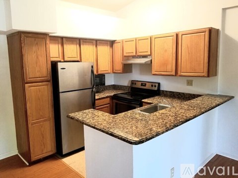 A kitchen with a granite countertop and wooden cabinets.