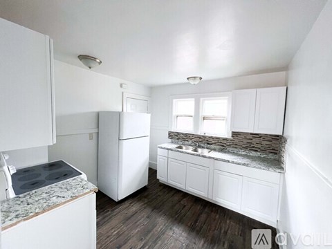 A kitchen with white cabinets and a granite countertop.