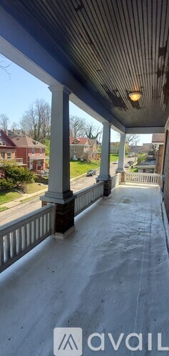 A porch with white columns and a wooden ceiling.