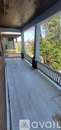 A porch with a wooden ceiling and white columns.