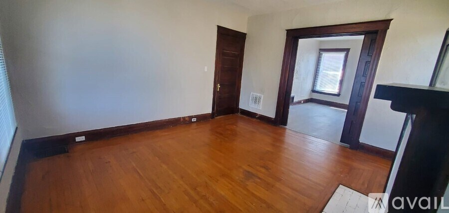 A room with wooden floors and a door leading to another room.