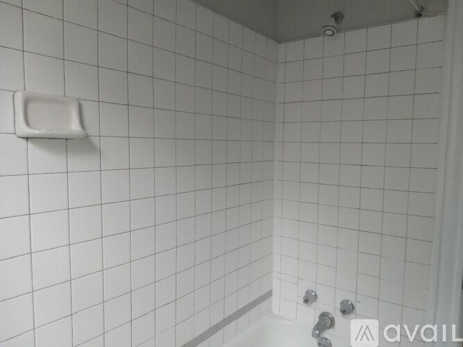 A white tiled shower with a white tub spout.