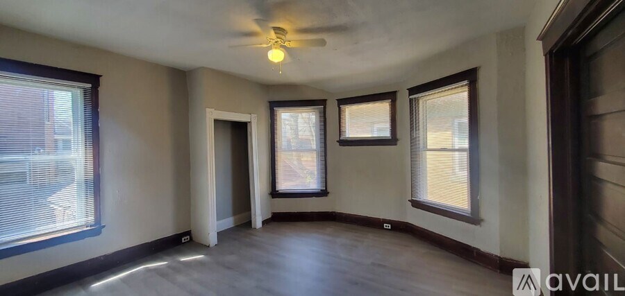 A room with a ceiling fan and three windows.