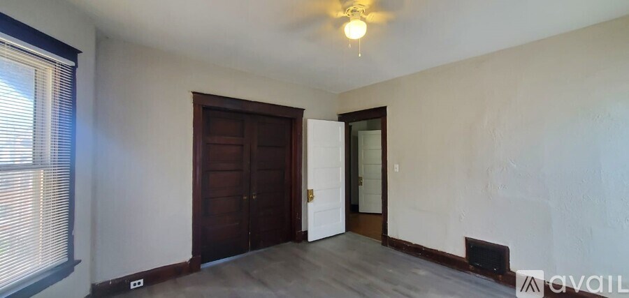 A room with a brown door and a window with blinds.