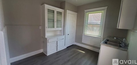 A kitchen with white cabinets and a window.