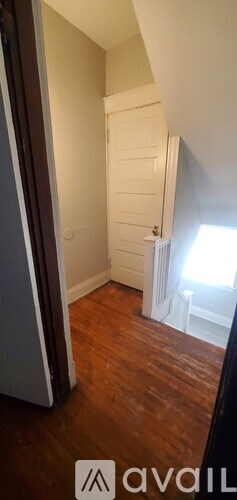 A hallway with wooden floors and white walls.