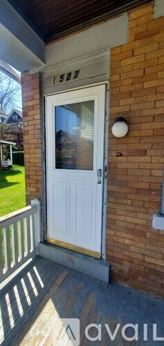 A white door with the number 1527 on the brick wall above it.