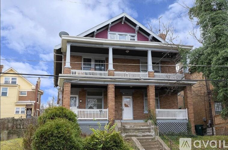 A two-story house with a red roof and white trim is for sale.