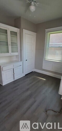 A room with a wooden floor and white cabinets.