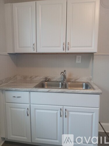 A kitchen with white cabinets and a marble countertop.