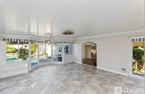 A spacious room with a marble floor and a ceiling fan.