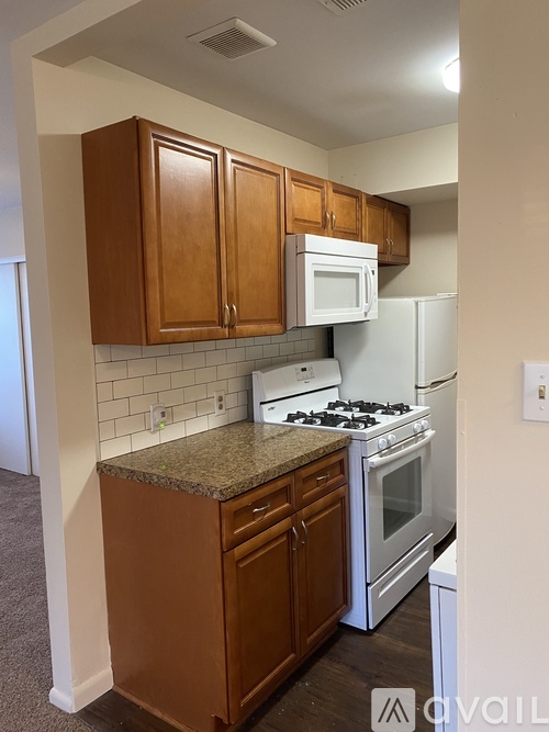 A kitchen with brown cabinets and white appliances.
