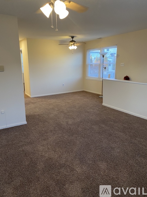 A spacious room with carpeted floor and a window with blinds.