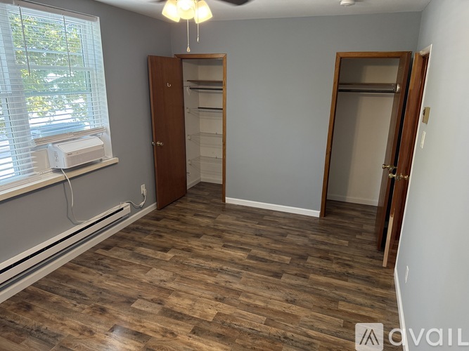 A room with wooden flooring and a window with blinds.