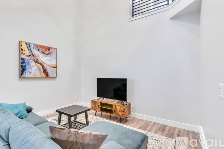 A living room with a blue couch, a wooden coffee table, and a painting on the wall.