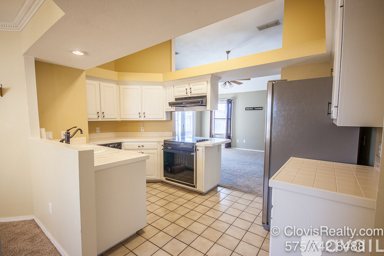 A kitchen with white cabinets and a black fridge.