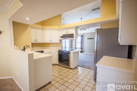 A kitchen with white cabinets and a black fridge.