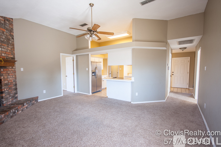 A spacious living room with a fireplace and a ceiling fan.