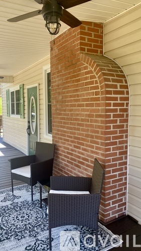 A patio with a brick column and a black and white chair.