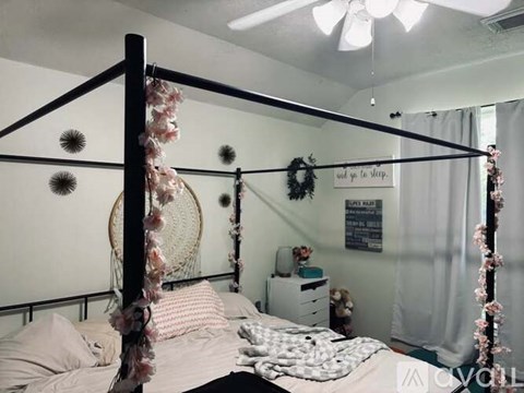 A bedroom with a four poster bed and a wreath on the wall.