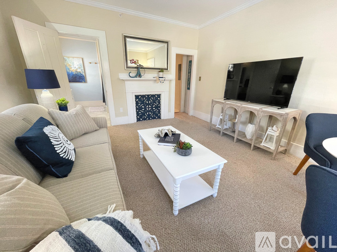 A living room with a white couch, a white coffee table, and a television.