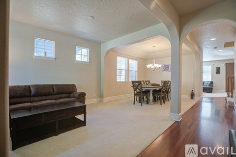 A living room with a brown leather couch and a dining table with chairs.