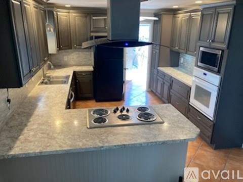 A kitchen with a black refrigerator and a stove top oven.