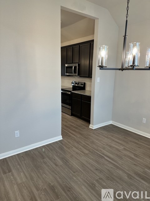 A kitchen with dark brown cabinets and a light wooden floor.