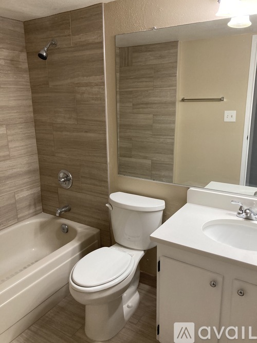 A white toilet sits next to a bathtub in a bathroom.
