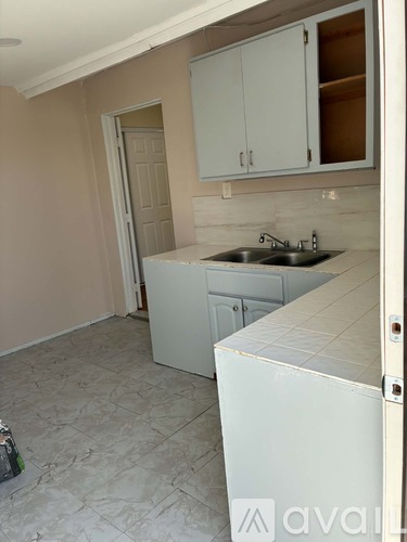 A room with a white fridge and a white door is shown.