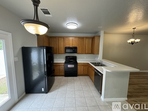 A kitchen with a black fridge, wooden cabinets, and a white island.