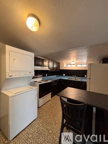 A kitchen with a white stove top oven and black countertops.