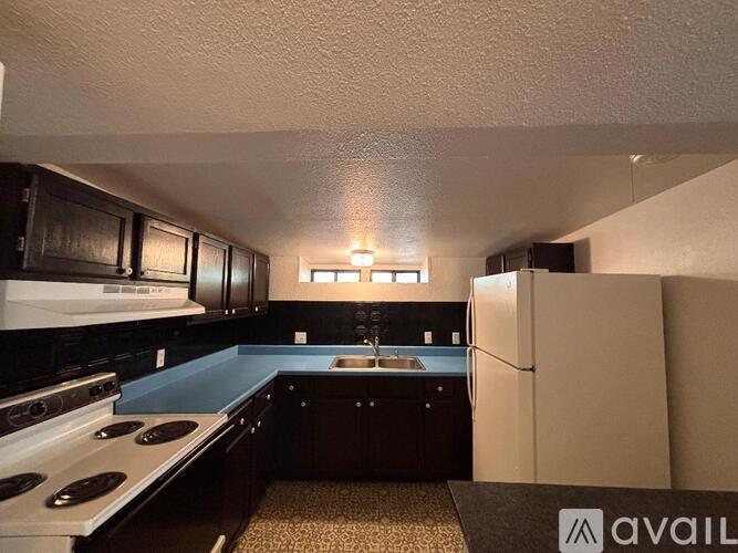 A kitchen with black cabinets and a white fridge.