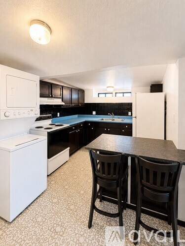 A kitchen with black cabinets and a white refrigerator.