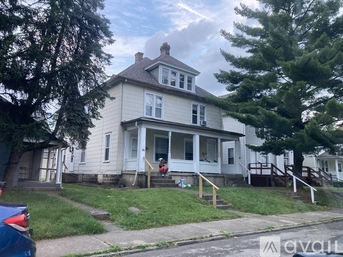 A two-story house with a white front porch and a brown roof.