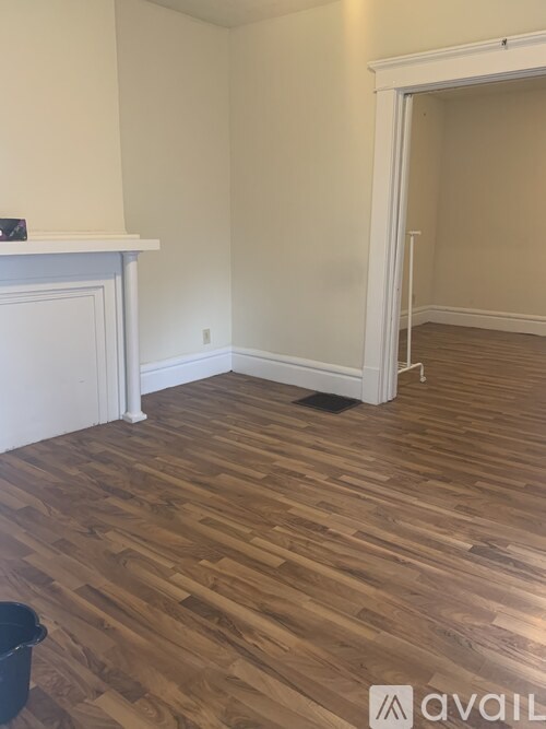 A room with wooden flooring and a fireplace.