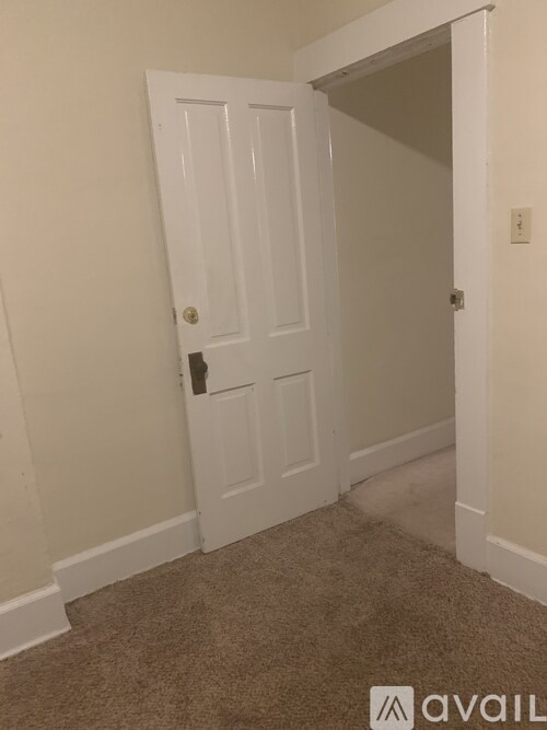 A white door is in a room with carpeting.