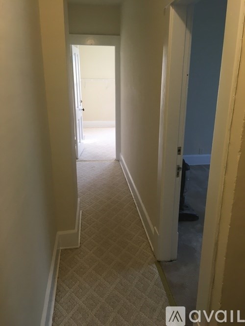 A hallway with a carpeted floor and walls painted in a light color.