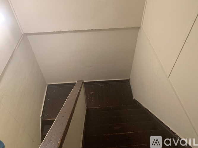 A staircase with a wooden handrail and dark steps.