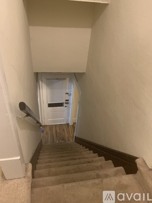 A staircase with beige carpeted steps leading to a white door.