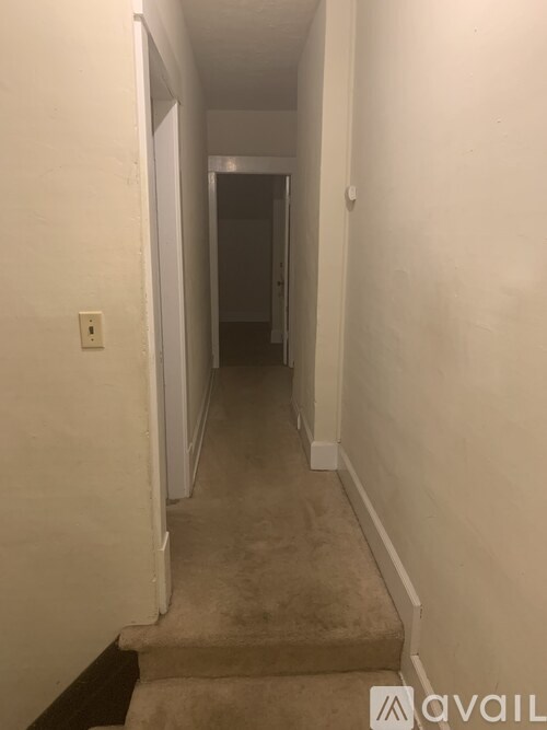 A hallway with a carpeted floor and white walls.
