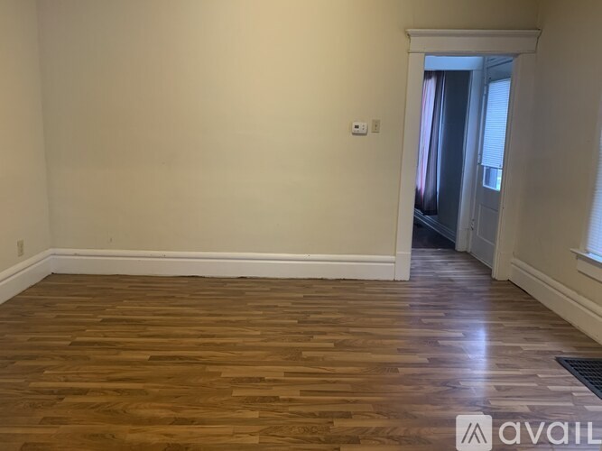 A room with wooden flooring and white walls.