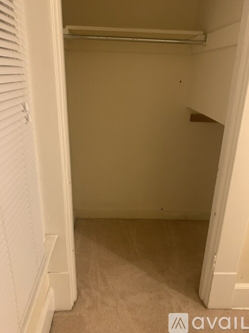 A small, empty room with white walls and a carpeted floor.