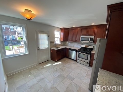 A kitchen with brown cabinets and a white tiled floor.